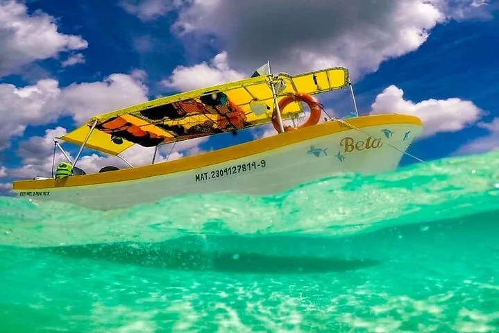 Ein kleines gelb-weißes Boot namens „Beto“, das in klarem türkisfarbenem Wasser vor Anker liegt.