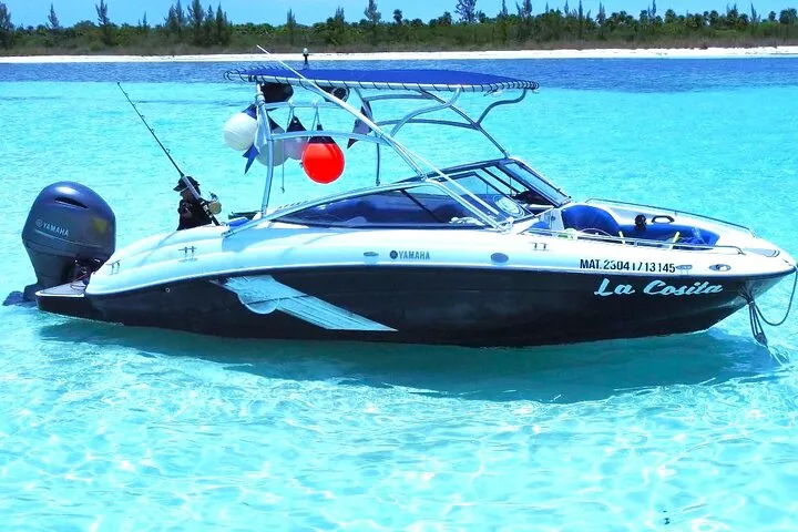 Ein kleines Boot namens „La Cosita“, das in flachem türkisfarbenem Wasser nahe der Küste vor Anker liegt.
