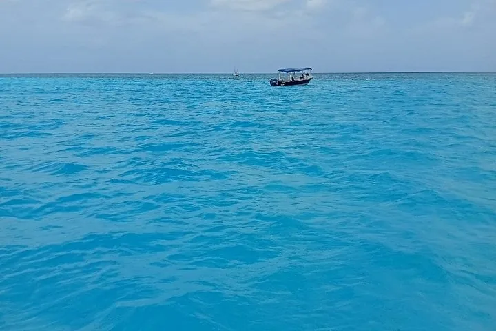 Ein kleines Boot, das in den weiten leuchtend blauen Ozeangewässern vor Anker liegt.